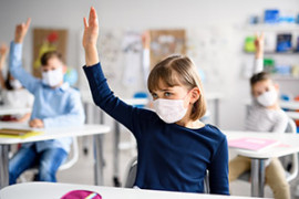 Schülerin mit Mund- und Nasenschutz Schülerin mit Mund- und Nasenschutz meldet sich im Klassenraum