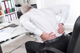 Rückenschmerzen - Berufskrankheit Mann im Büro mit Rückenschmerzen