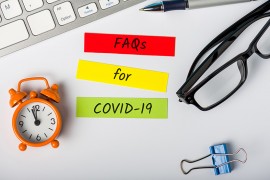 Fragen und Antworten zu Rechten und Pflichten im Pandemiefall Tastatur, Kugelschreiber, Post-its auf Bürotisch
