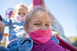 Mädchen mit Halstuch vor dem Mund